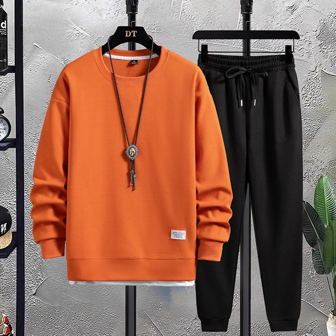 Oranje heren joggingpak met lange mouwen en zwarte joggingbroek, casual sportkleding, comfortabele pasvorm, ideaal voor dagelijks gebruik.