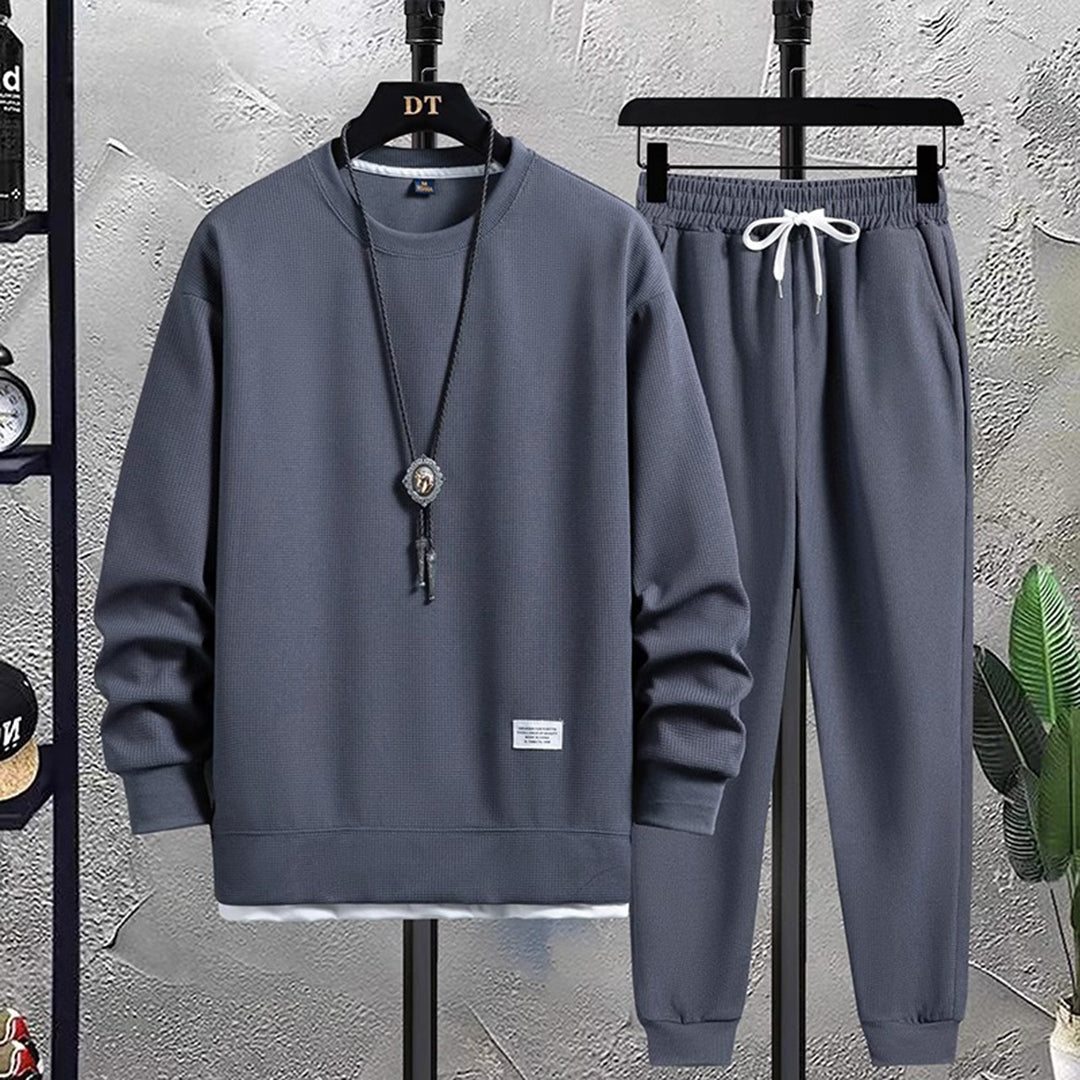 Grijs heren joggingpak, bestaande uit een sweatshirt en joggingbroek, casual sportkleding, comfortabele pasvorm, ideaal voor dagelijks gebruik.
