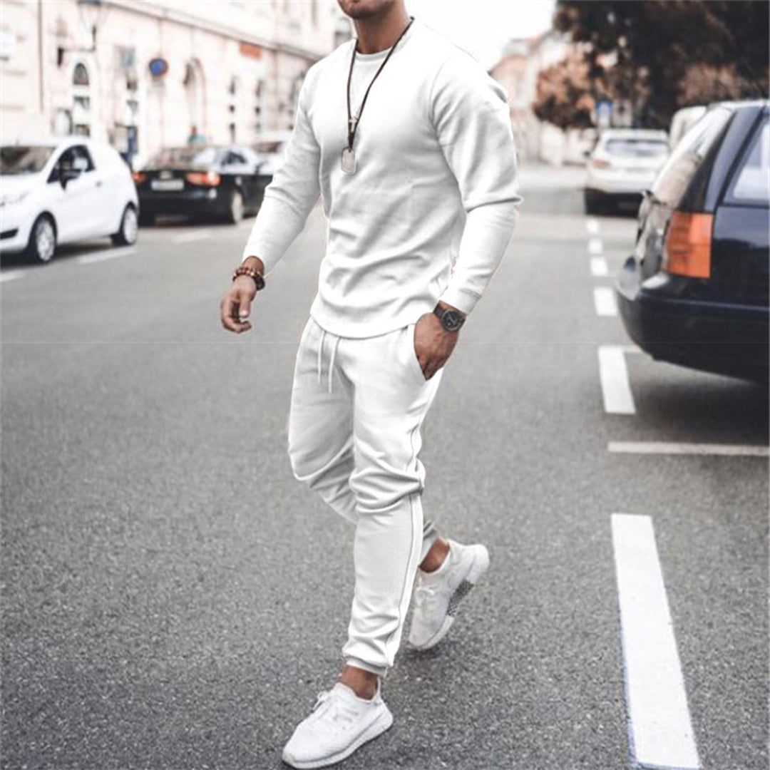 Man in wit trainingspak en sneakers loopt op straat; modieuze sportkleding, casual outfit, stedelijke stijl, comfortabele pasvorm.