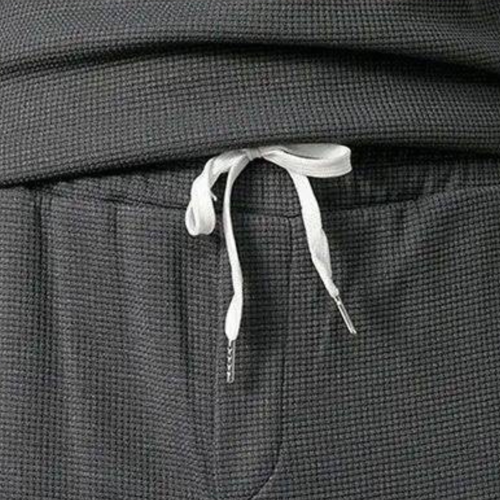 Donkergrijze joggingbroek met witte trekkoord, textuur van wafelstof. Comfortabele loungewear, ideaal voor casual en sportieve outfits.